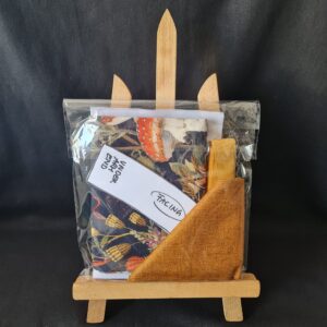 Fabrics and swatches in a gift package, featuring floral printed fabric, textured gold tone fabric, and coordinating ribbons, ideal for sewing, tailoring, or craft projects.