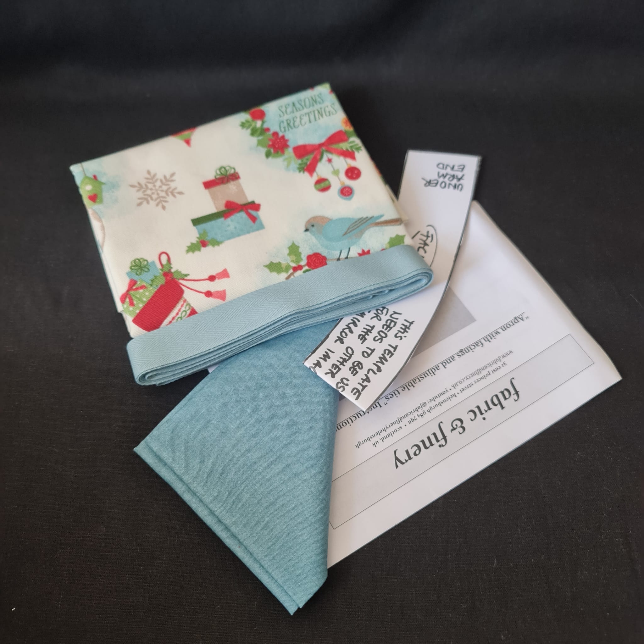 Colourful Christmas fabric bundle with festive prints and coordinating ribbons for sewing, quilting, or crafting holiday projects. Ideal for creating seasonal decorations or garments.