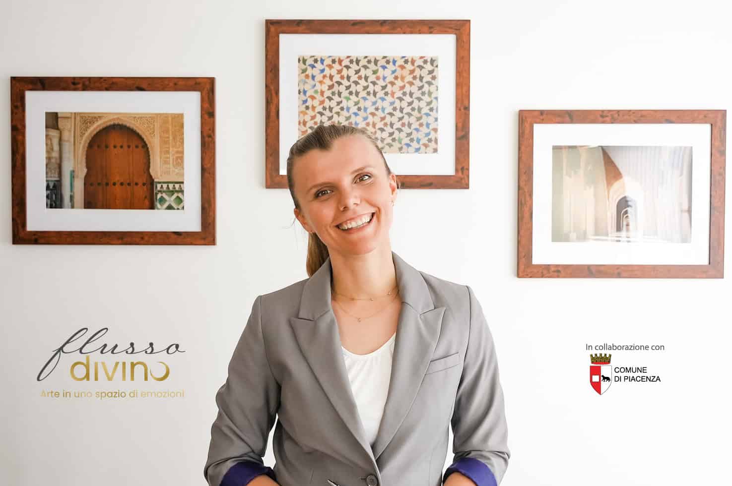 Un'illustrazione di una donna sorridente davanti a una parete decorata con quadri, rappresenta l'impegno di Flusso Divino nell'organizzare eventi artistici per artisti emergenti che uniscono esperienz.