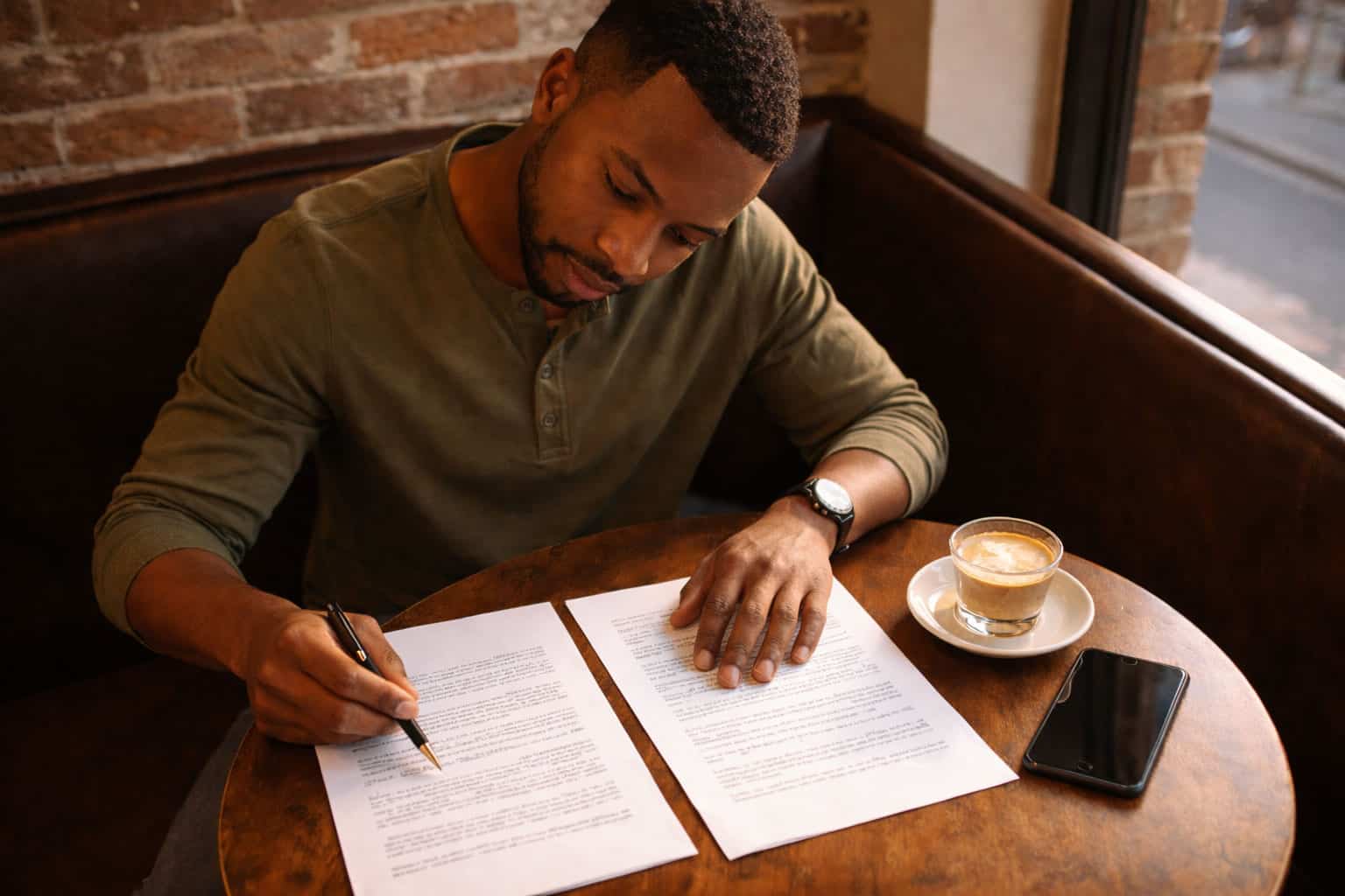 Man at coffee shop comparing health insurance plan documents side by side