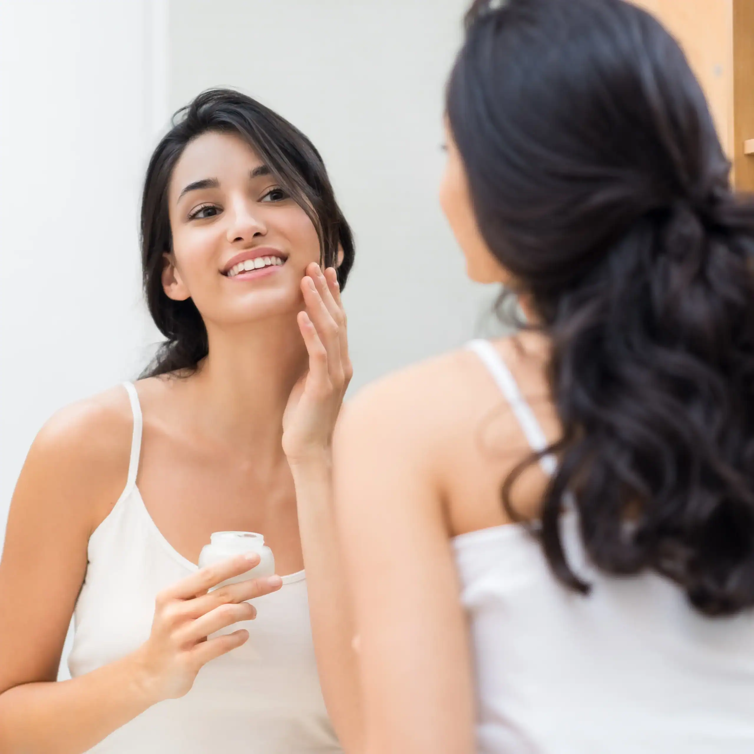 Woman applies a cream to her face