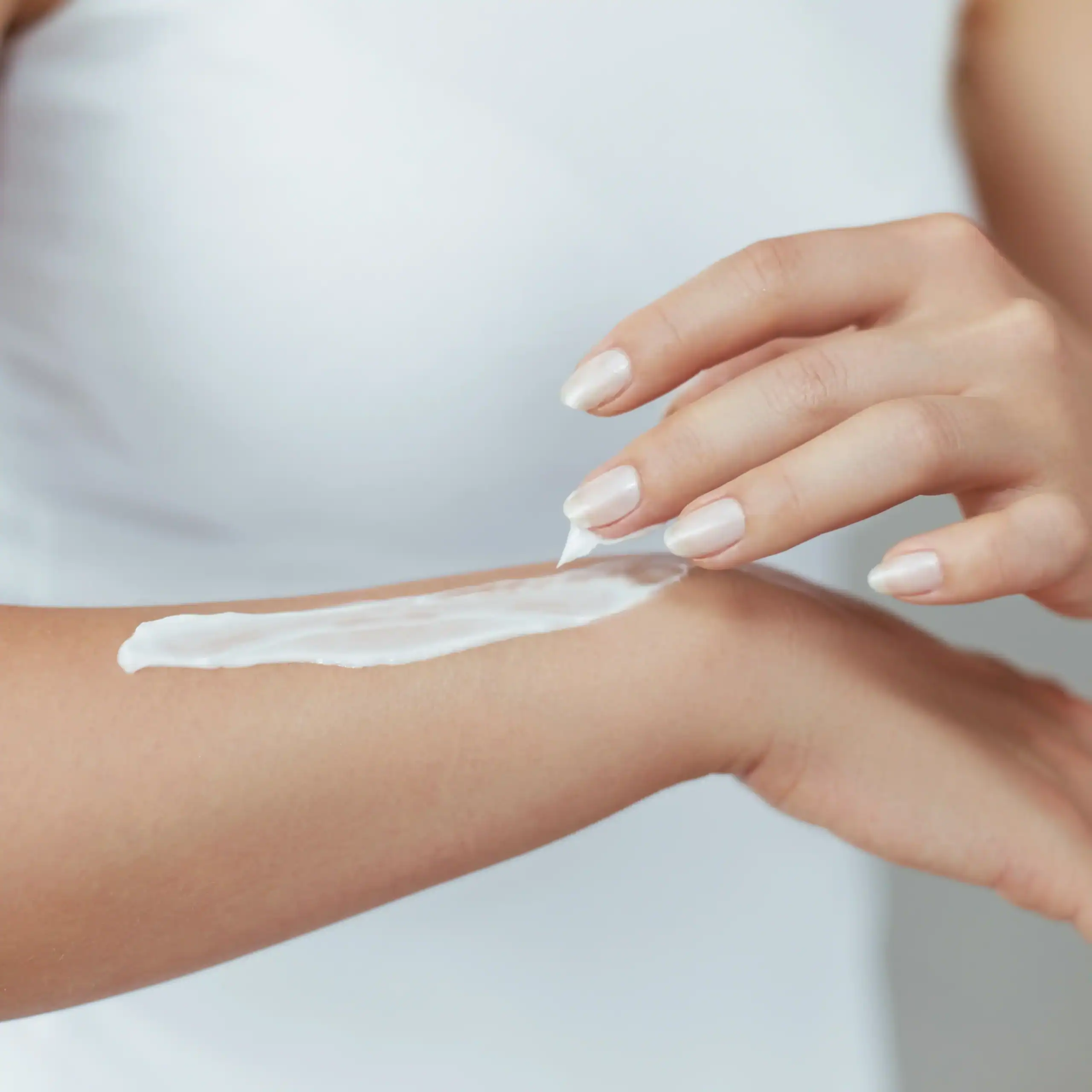 Woman puts cream on her arm
