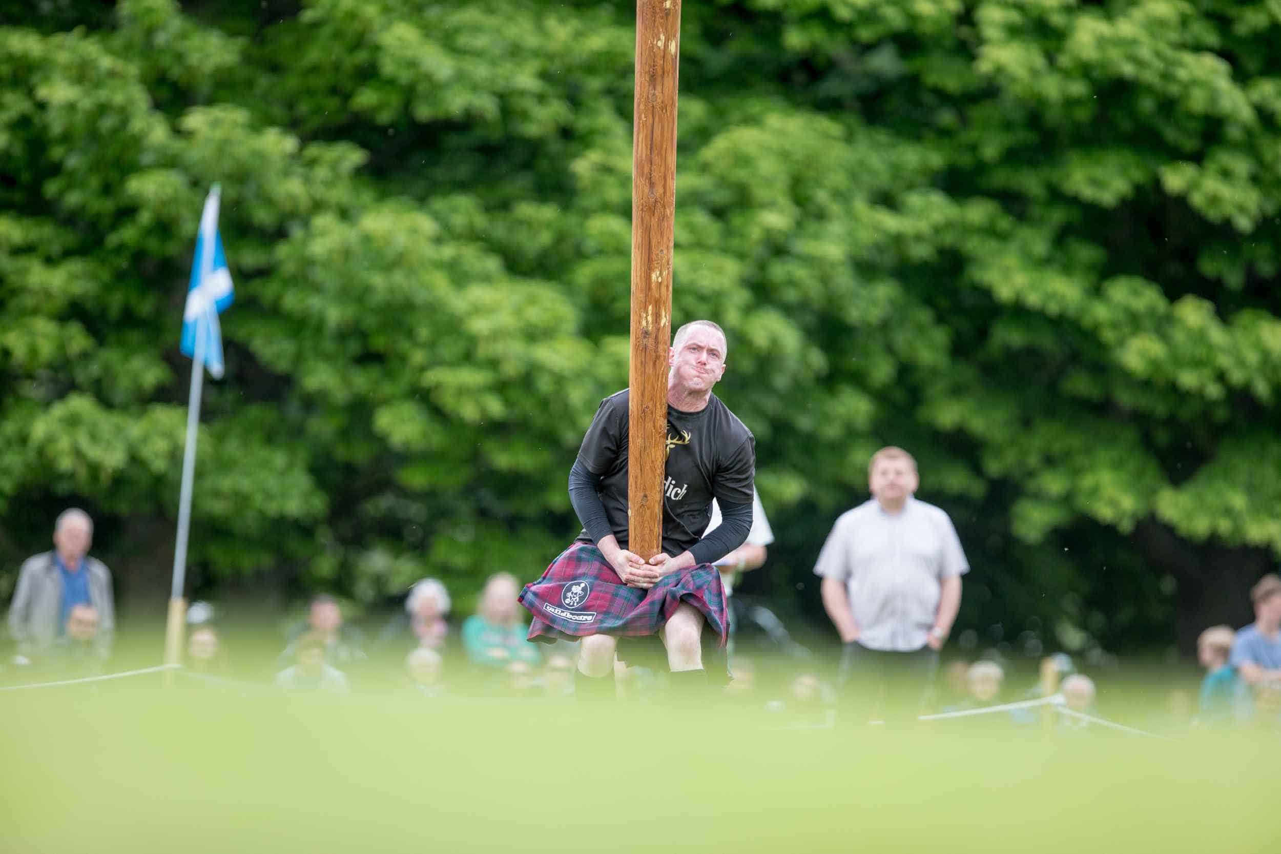 Competitor lifting caber during Gordon Castle Highland Games caber toss