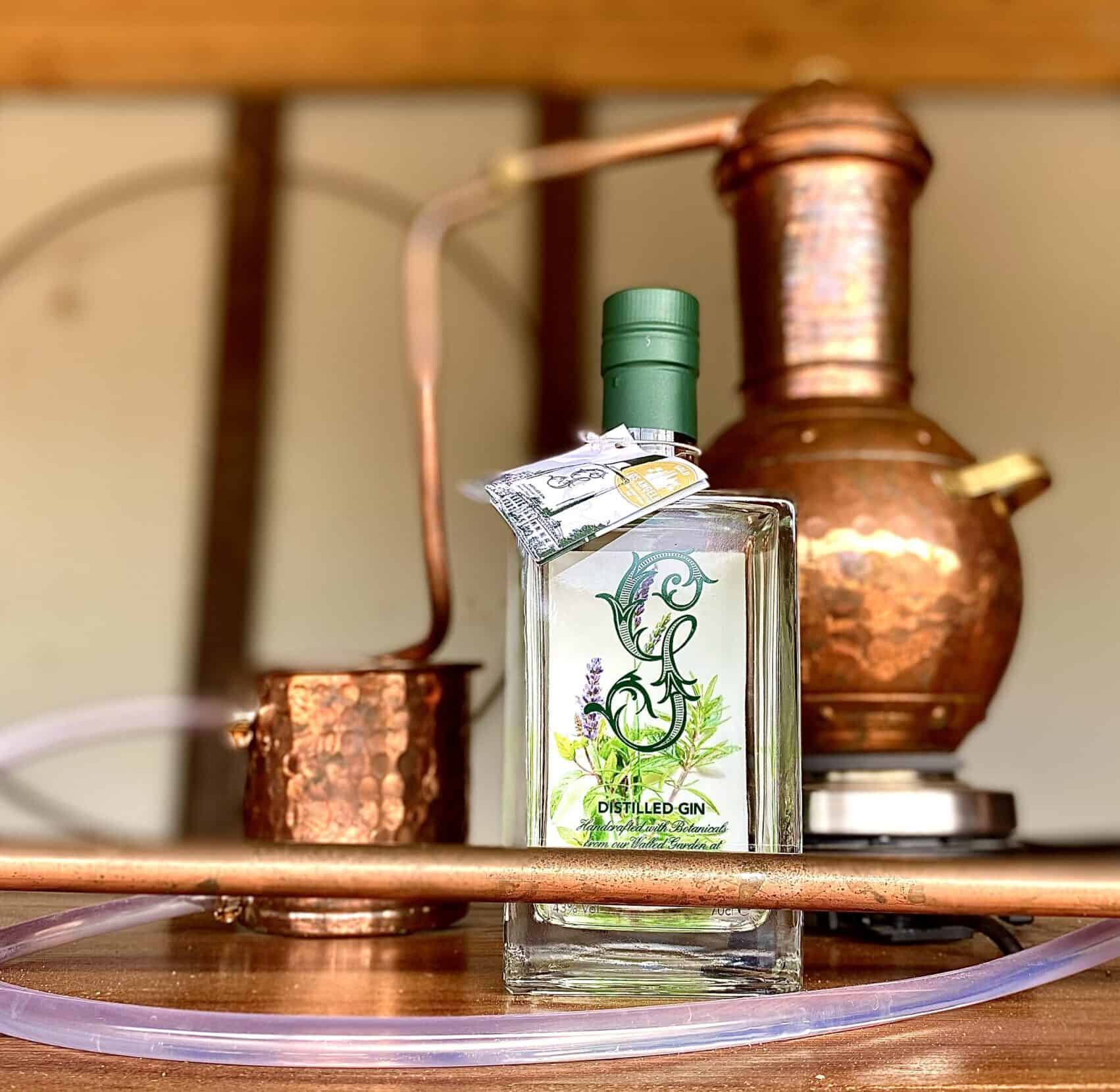 Bottle of Gordon Castle Walled Garden Gin beside copper still