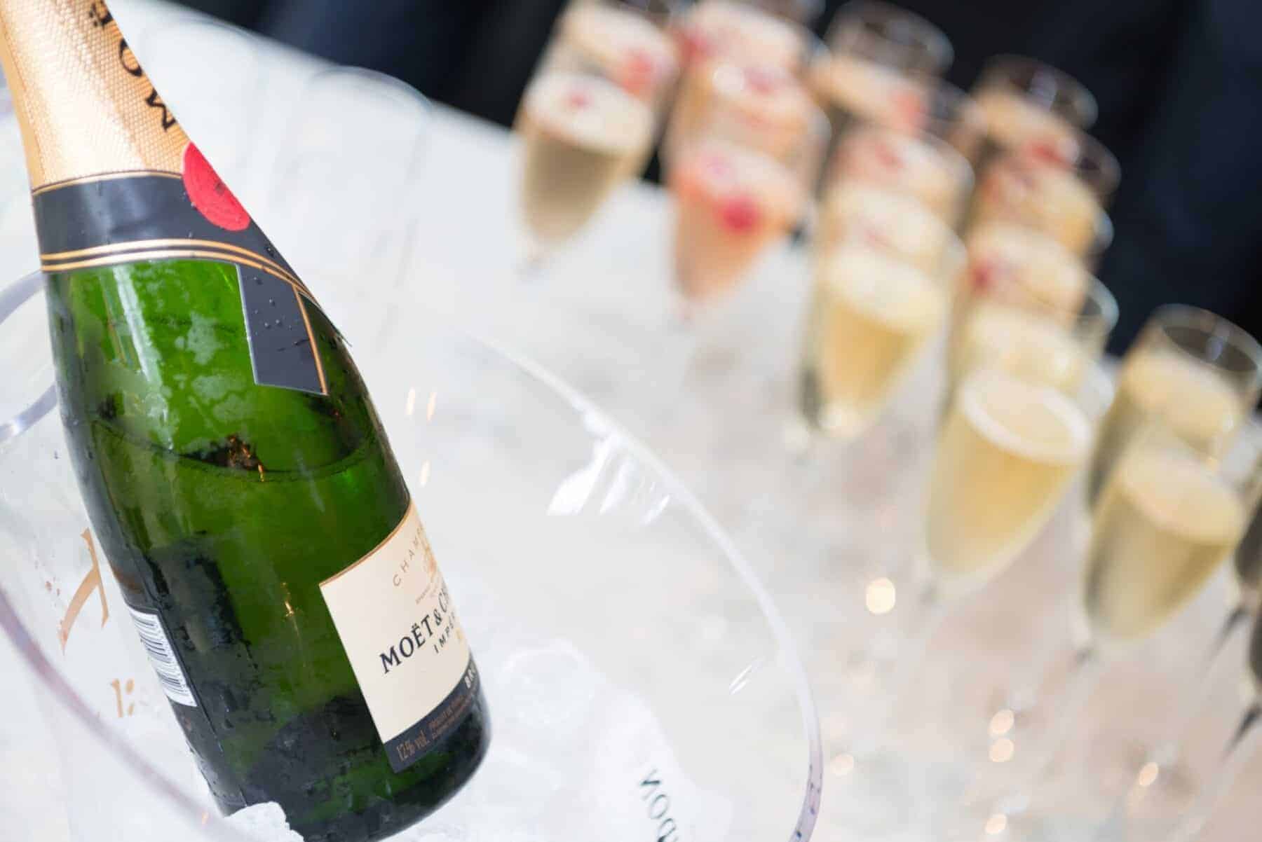 Champagne bottle chilling in an ice bucket with flutes of champagne in the background, ready for a celebration or special event. Perfect for weddings, parties, or festive gatherings.