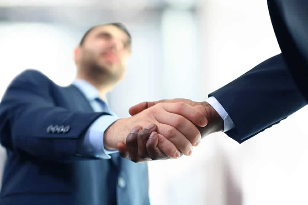 Close-up of two businessmen shaking hands in a modern office environment.