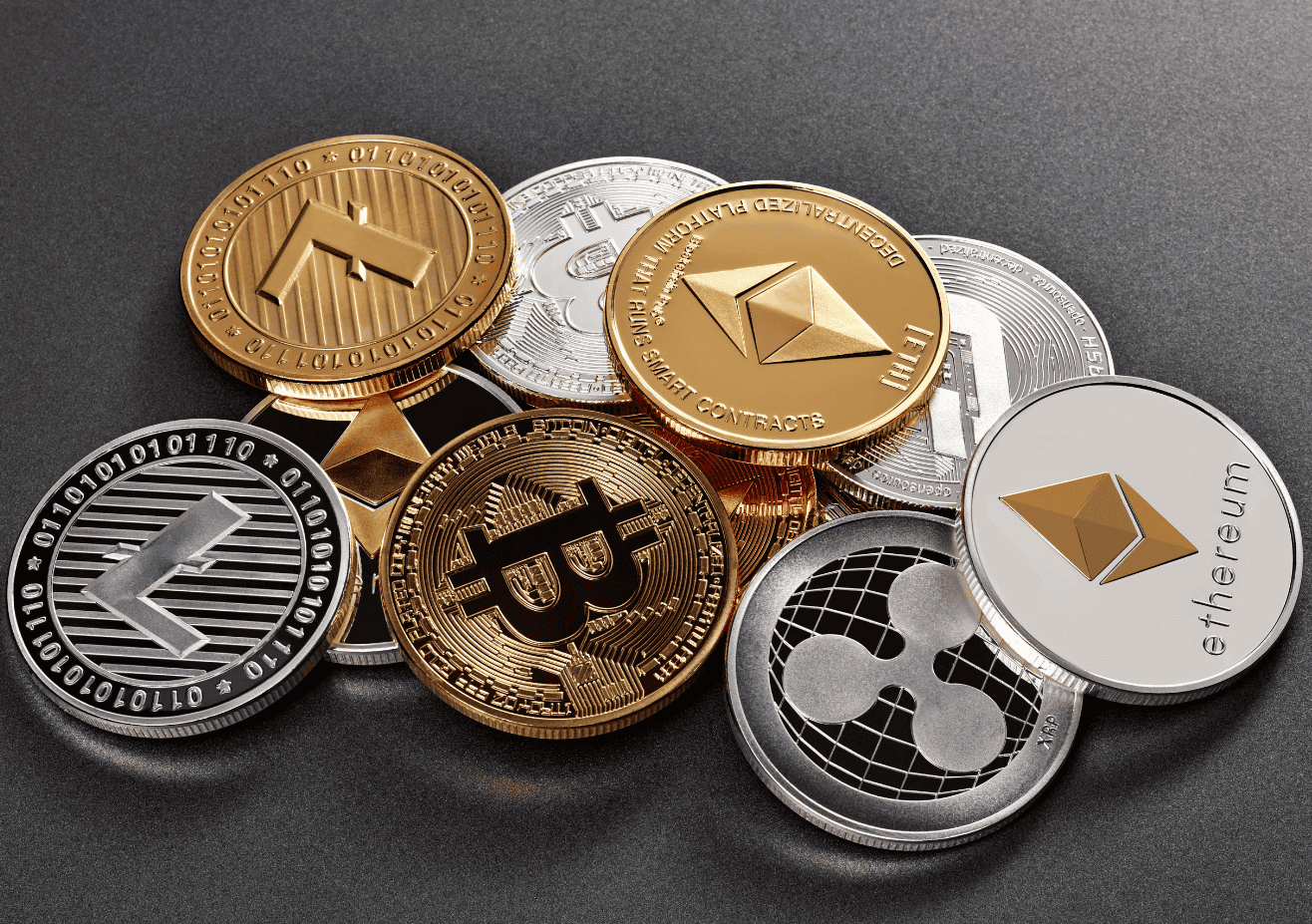 Cryptocurrency coins including Bitcoin, Ethereum, Ripple, and Litecoin displayed on a dark surface. Digital currencies are symbolised by metallic tokens with iconic logos.