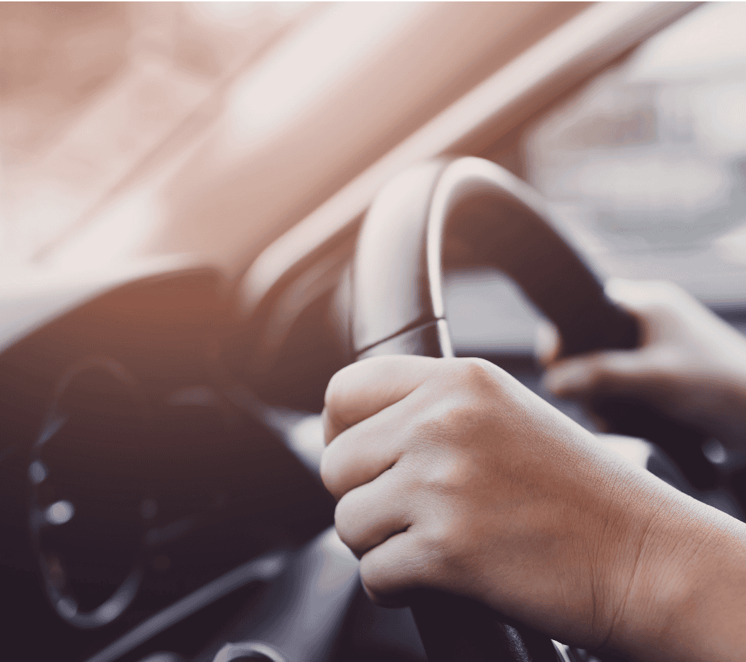 Modern hand gripping a steering wheel while driving a car, close-up in natural light.