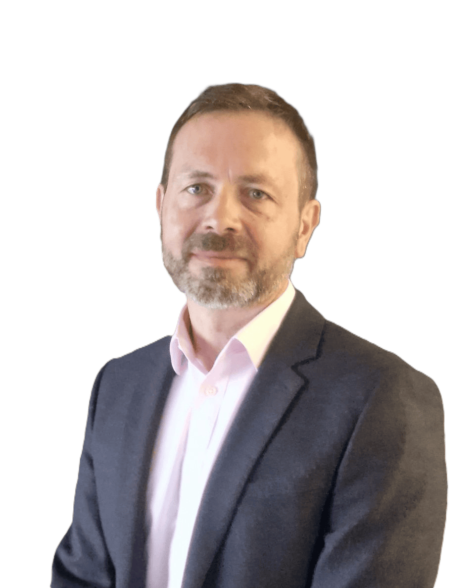 Professional man in business attire with a grey blazer and light pink shirt standing against a textured grey stone wall.