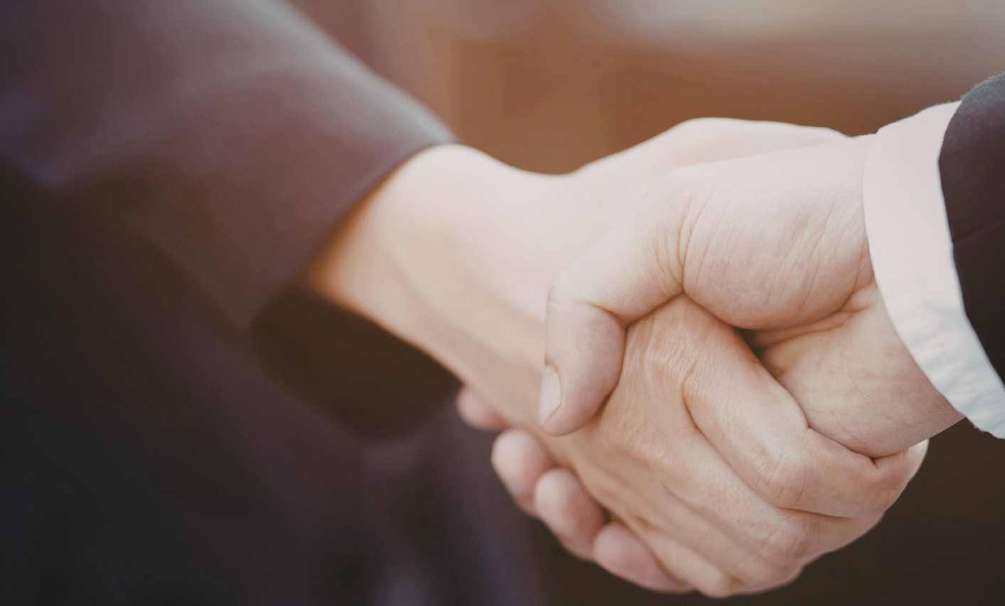 Close-up of two people shaking hands, symbolising trust and agreement in a professional setting.