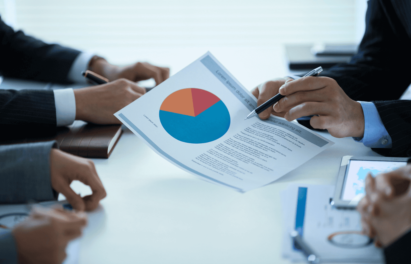 Business professionals discussing financial data and charts during a meeting in a modern office setting.
