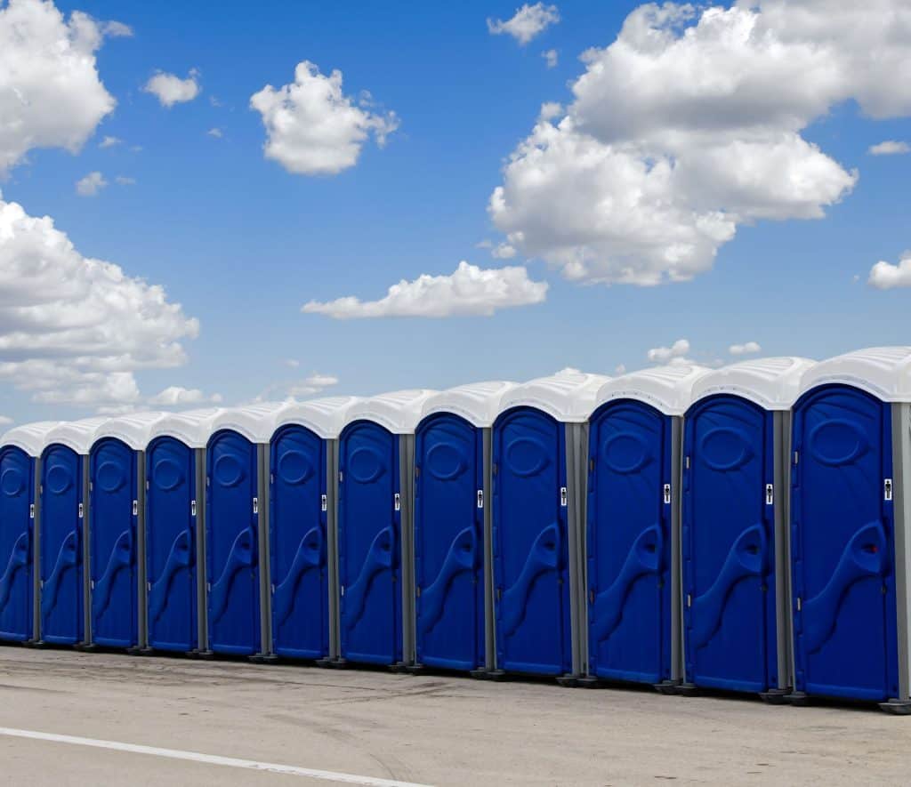 Row of blue portable restrooms under a partly cloudy sky.