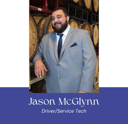 Jason McGlynn, driver and service tech at VannGo, standing in warehouse with barrels.
