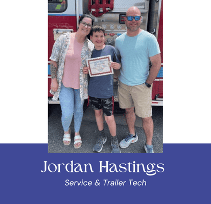 Jordan Hastings with family holding certificate in front of fire truck.