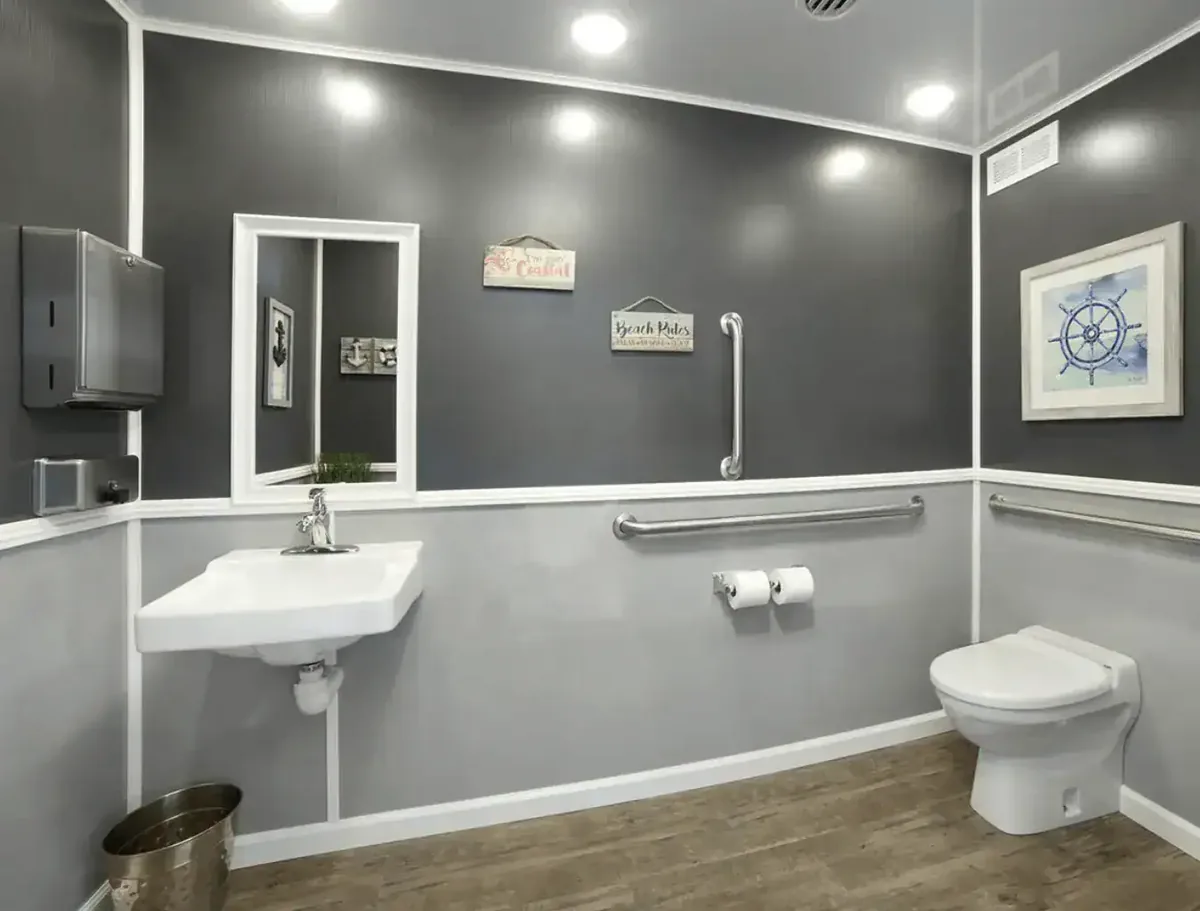 Clean interior of a VannGo ADA restroom trailer with grab bars, sink and toilet