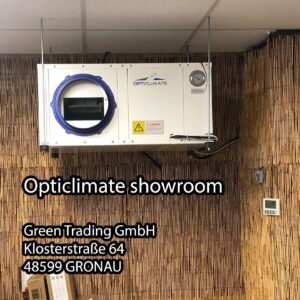 Lüftungssystem von OptiClimate, installiert im Showroom der Green Trading GmbH. Das System ist für die Regulierung der Klimabedingungen in Innenräumen konzipiert. Das Gerät verfügt über eine robuste Konstruktion mit weißem Finish und einem blauen Lufteinlass. Die Bedienung wird durch ein analoges Manometer zur Druckkontrolle vereinfacht. Dieses Produkt ist auf Energieeffizienz und Langlebigkeit ausgelegt, was zum umweltfreundlichen Charakter der Anlage beiträgt. Das System eignet sich hervorragend für den Einsatz in Gewächshäusern und anderen Anwendungen, bei denen eine Klimasteuerung erforderlich ist.