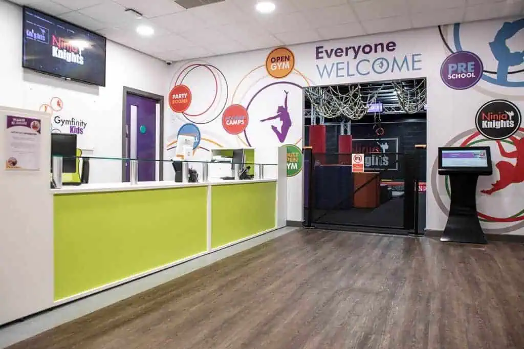 Gym reception area with bright colours and a sign for Ninja Knights indoor climbing gym and activity centre.