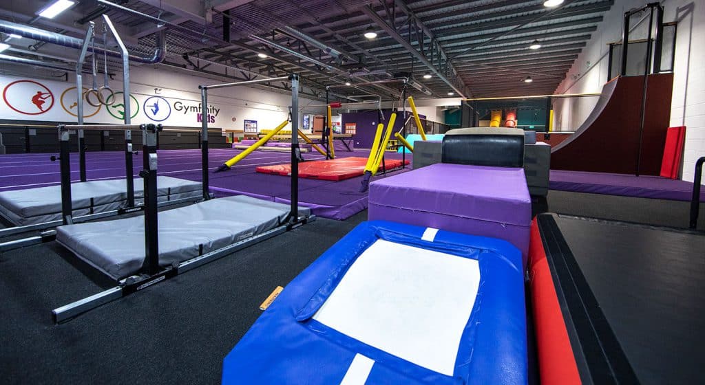 Indoor gymnastics and trampoline park with various climbing frames, foam pits, and activity zones for kids. Bright, colourful, and safe space for children to play and develop their athletic skills.