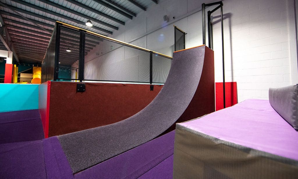 Jumping trampoline with safety padding inside an indoor playground.