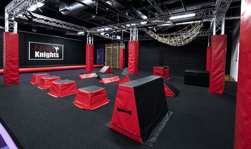 Climbing gym with various obstacle courses, padded mats, and rope climbs designed for ninja-style fitness training at Ninja Knights.