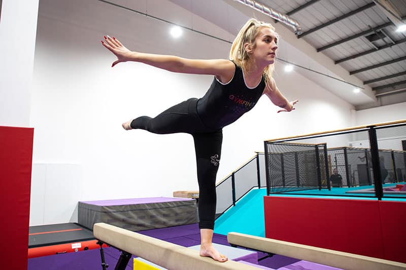 Gymnast performing balance pose on vaulting table at a gymnastics training centre in the gym hall.