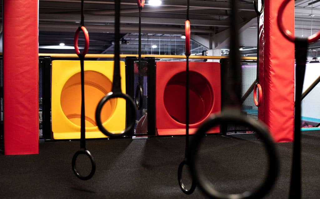 Yellow and red climbing holds and gymnastic rings in an indoor sports training facility, designed for strength and agility workouts.