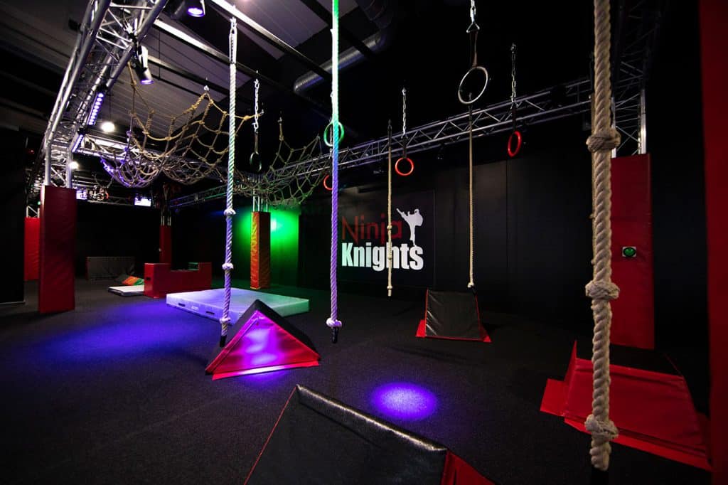 Climbing adventure zone with ropes, rings, and obstacle equipment at Ninja Knights indoor activity centre. Equipped with colourful lighting and padded flooring for safety.
