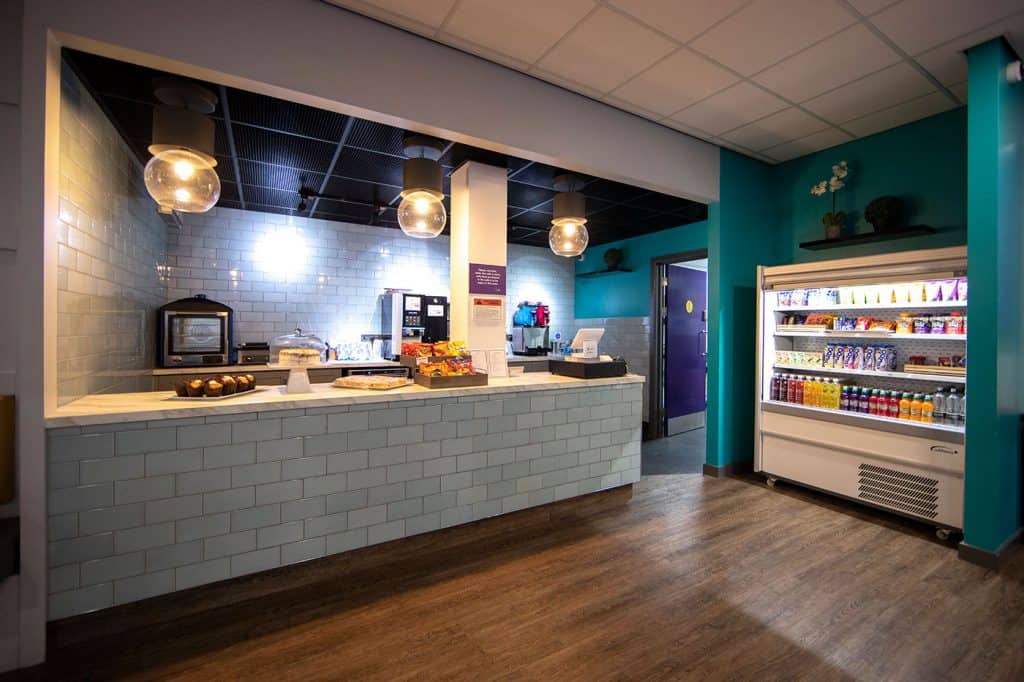 Hot drink and snack area with vending machine in a modern, colourful cafe or lounge setting.