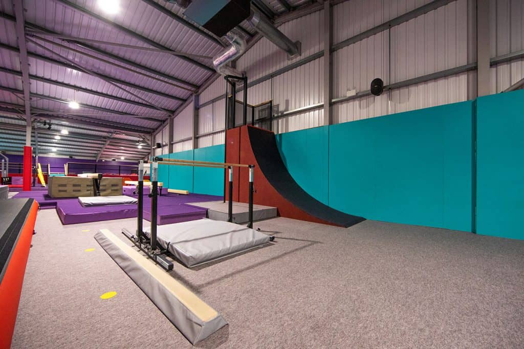 Colourful indoor trampolining park with foam pits and gymnastic equipment. Bright lighting and padded flooring create a safe environment for recreational bouncing and trampoline activities.