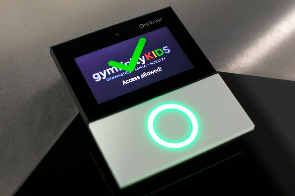 Gympass access control device for children's gymnastics class allowing entry with green check mark on screen.