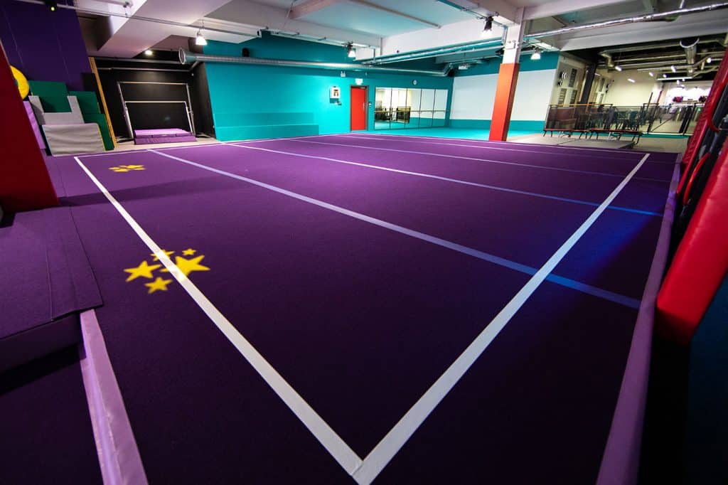 Purple indoor trampoline park with safety padding and designated jumping zones, featuring colourful walls and a modern, vibrant atmosphere for recreational activities.