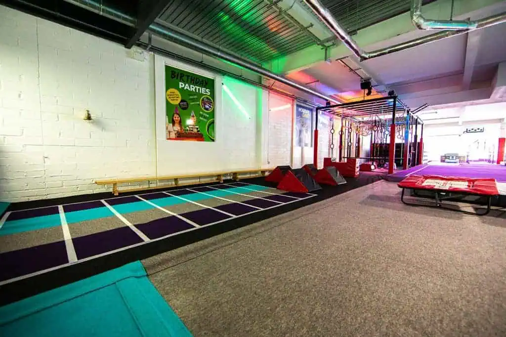 Jumping castle indoor play area with gymnastic mats and colourful lighting for children's entertainment.
