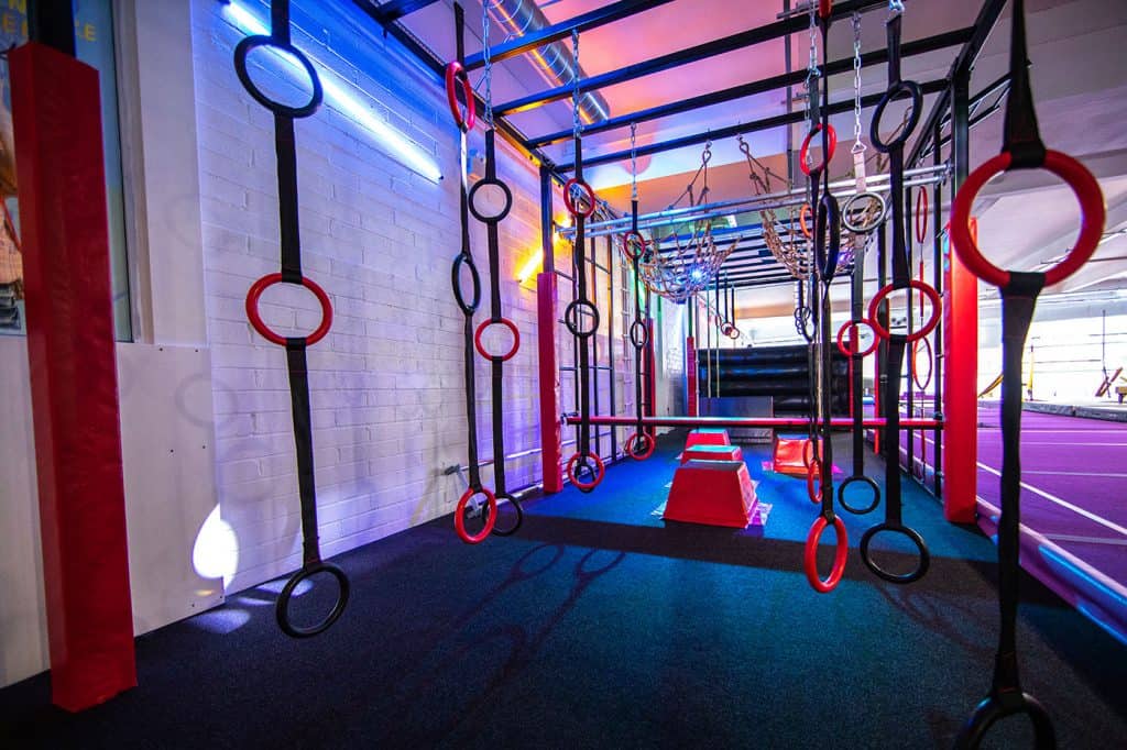 Climbing and gymnastic rings station with colourful lighting in an indoor fitness or Ninja Warrior training gym.