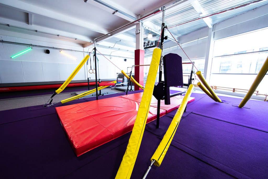 Trampoline park with safety padding and gymnastic equipment in a bright modern studio.