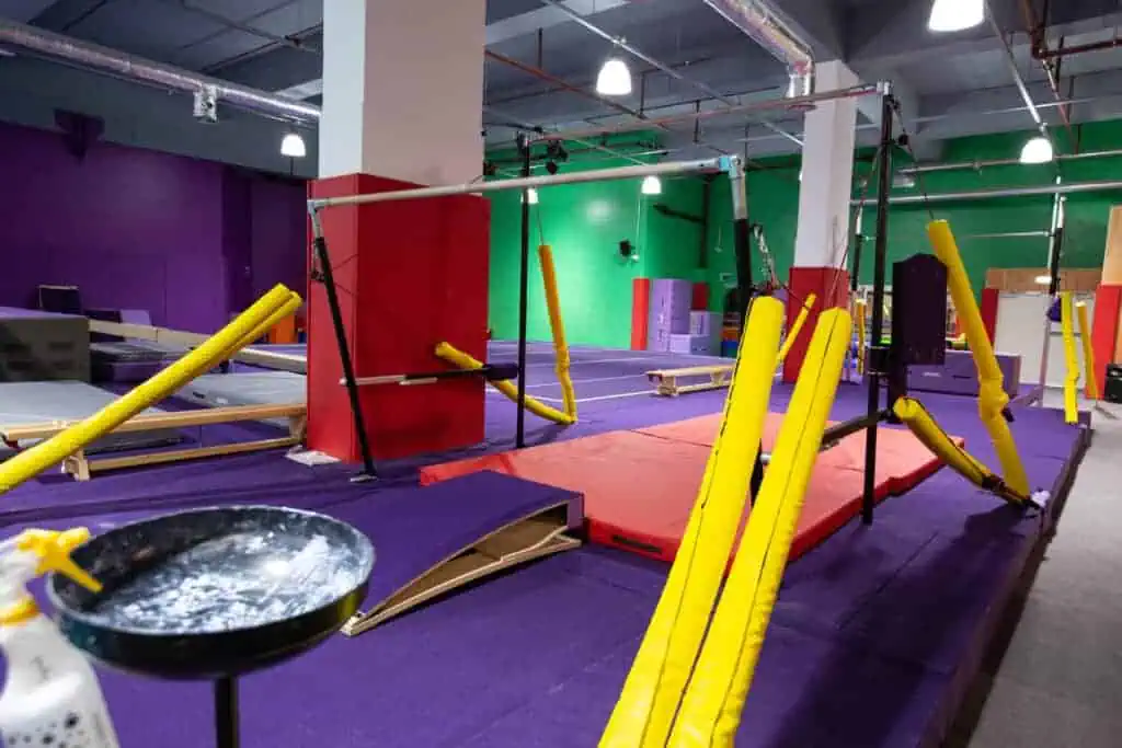 Climbing frame with padded mats and gymnastic equipment in an indoor soft play area for children.