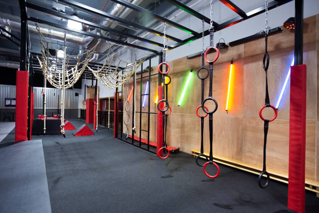Climbing gym with colourful lighting, climbing rings, ropes, and a web structure for fitness and recreational activities. Ideal for strength training, agility, and obstacle course challenges. Perfect for climbing enthusiasts.