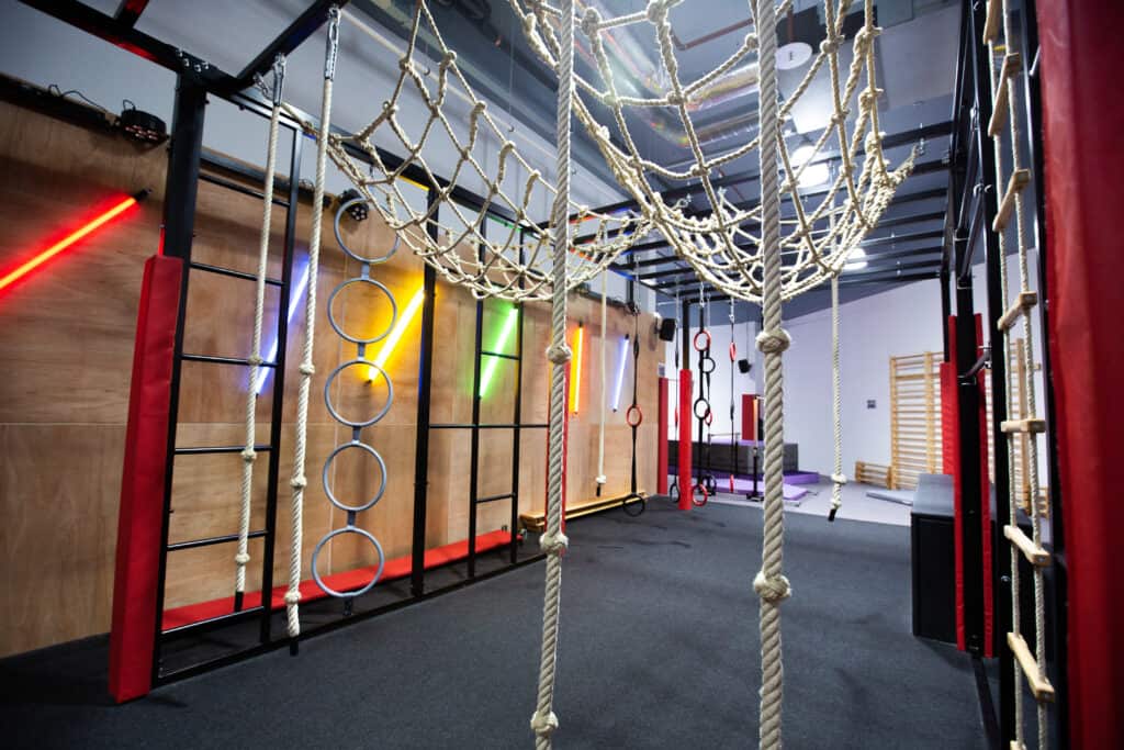 Climbing and obstacle course in an indoor activity centre with ropes, rings, and walls for kids' play and physical activity.