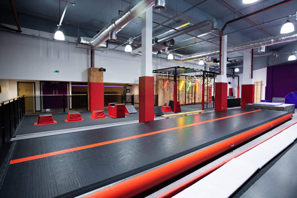 Trampoline park with foam pits and obstacle course for children and teens, bright interior with colourful gym equipment and safety padding, indoor recreational facility for active fun and training.