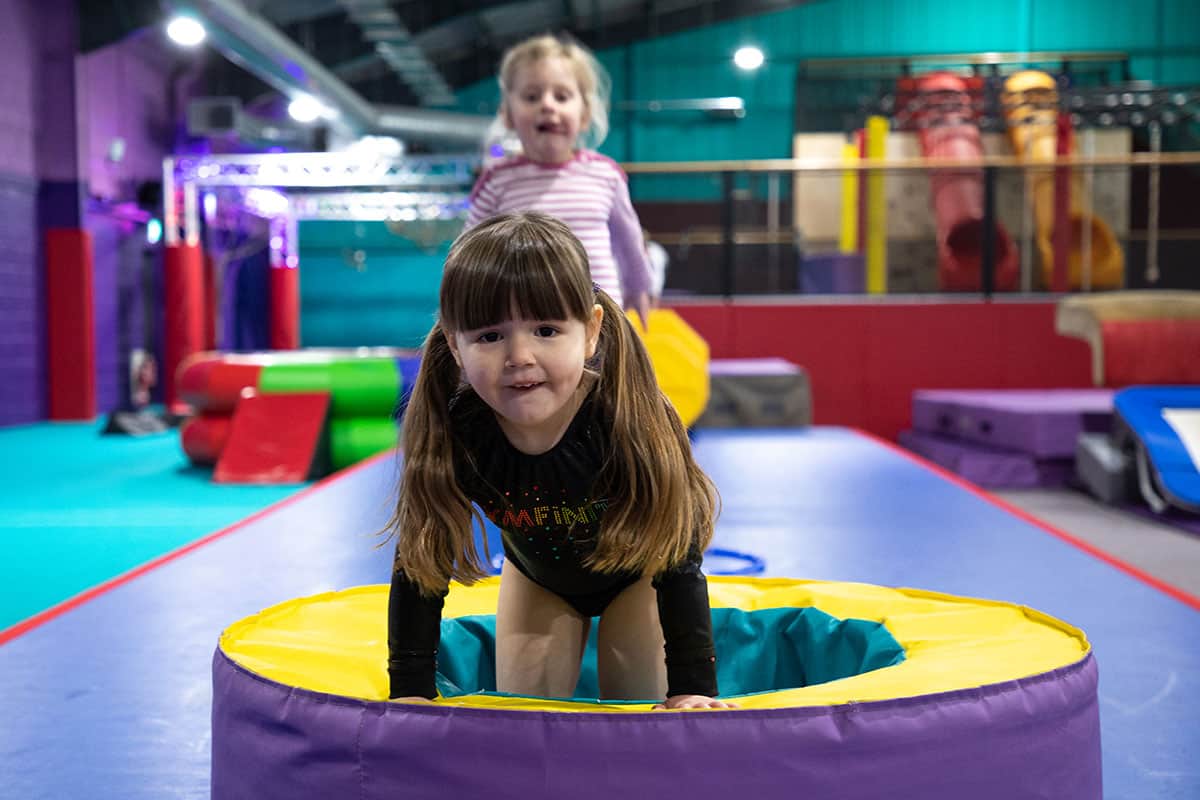 Colourful indoor trampoline park with kids having fun on the trampolines, vibrant padded flooring, and play equipment in the background. Perfect for children’s recreation and active play.