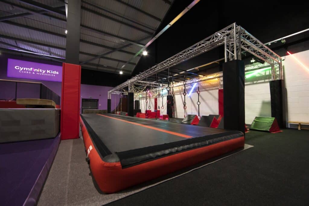 Trampoline park with aerial rings and colourful lighting inside Gymfinity Kids club.