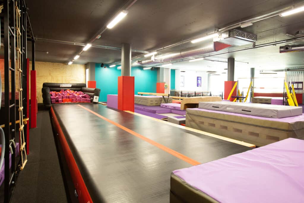 Colourful indoor trampoline park with padded safety zones, foam pits, and play structures for children and teens, offering fun and active entertainment in a safe environment.