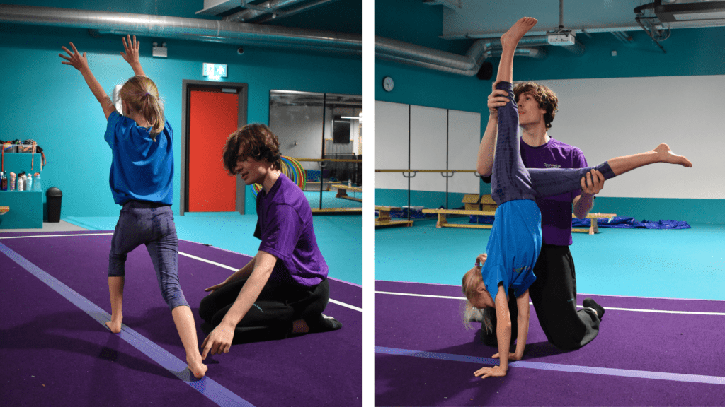 Girl practicing gymnastics with instructor on purple mat indoors, demonstrating handstand and flexibility, children engaging in gymnastics training, gym environment with equipment and mirrors, gymnastic class for kids.