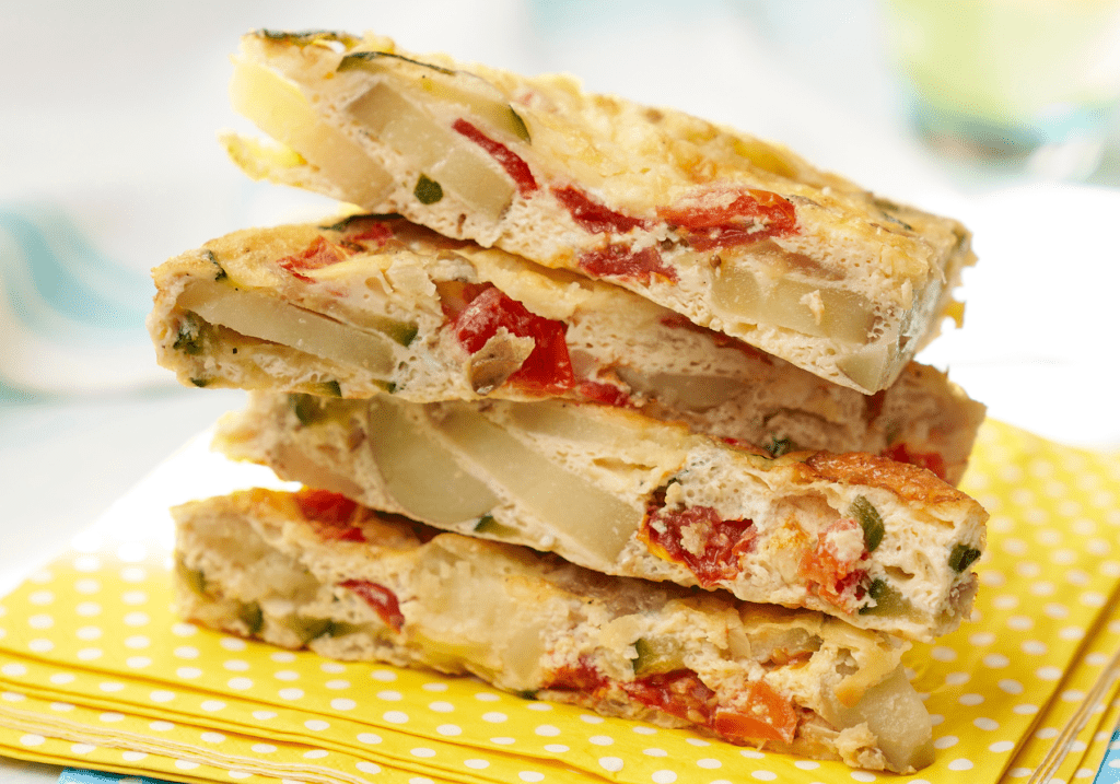 Rosti potato and vegetable frittata sliced and stacked on yellow napkin.
