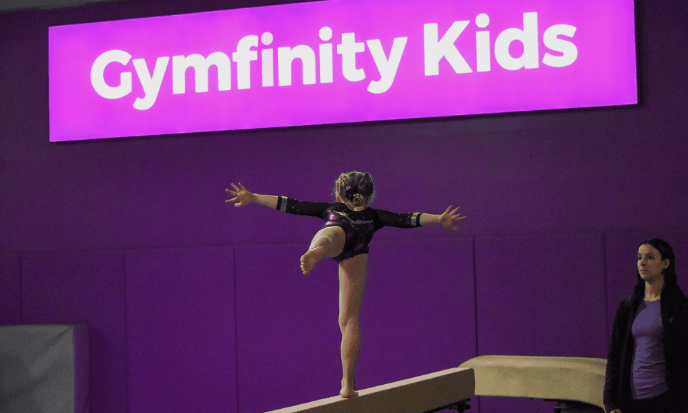Gymnastics young girl performing balance beam at Gymfinity Kids indoor sports centre.