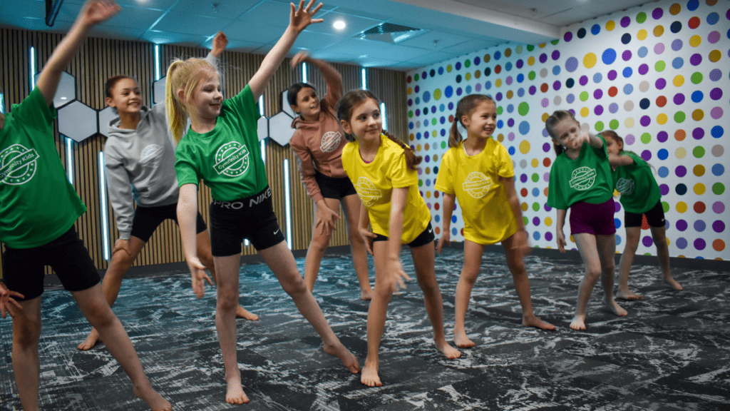 Energetic children in colourful sportswear participating in a dance or exercise class at the gym.