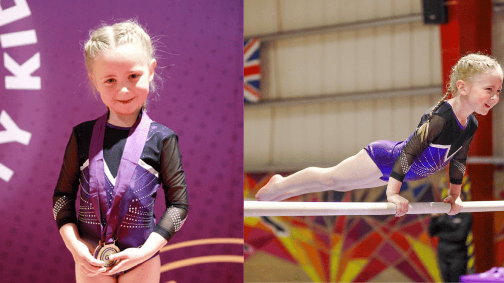 Medal-winning young gymnast wearing a black and purple leotard, holding her medal proudly.