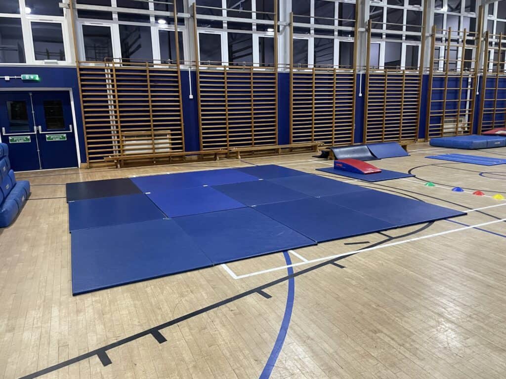 Folded gym mats and sports equipment in a school or sports hall.
