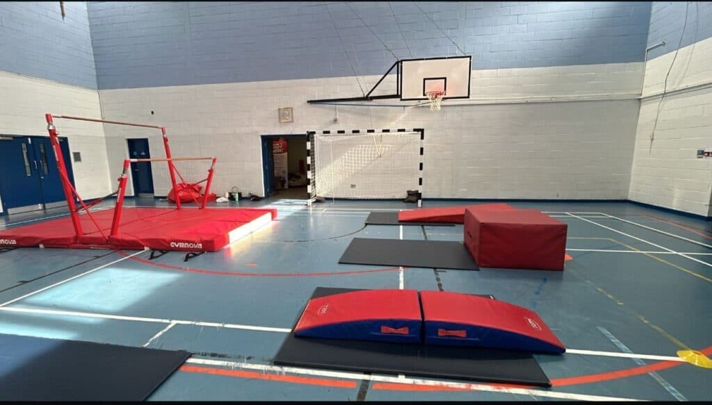 Climbing and gymnastics equipment set up in a school gymnasium for training or practice activities.