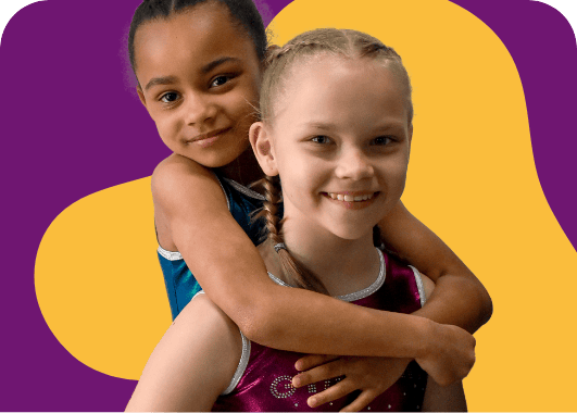 Happy young girls embracing each other with warm smiles, wearing colourful sportswear, against a vibrant purple and yellow background.