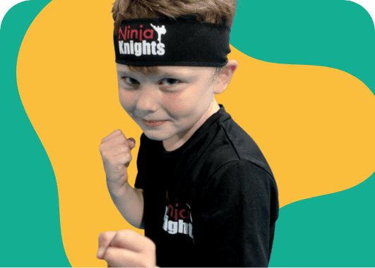 Young boy dressed as a ninja with a headband, striking a fighting pose against a colourful background.